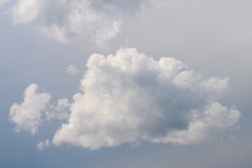 A fluffy cloud floats against a blue sky on a serene day, evoking relaxation and tranquility