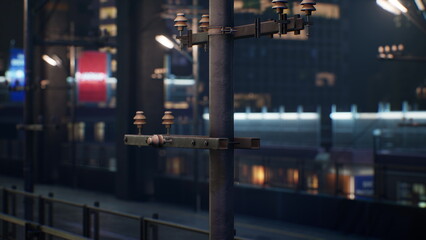 A utility pole stands tall against a vibrant cityscape at night. The train station glows with warm lights, creating an inviting atmosphere for evening travelers.