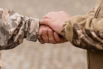 Military Hands Joining in Support  Camouflage Uniforms, Connection, Trust, Solidarity, Dusty Terrain, Warm Tones, Realistic Photography.