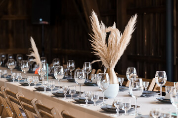 Elegant Wedding Reception Table Setting with Pampas Grass Centerpieces in Rustic Barn Interior,...