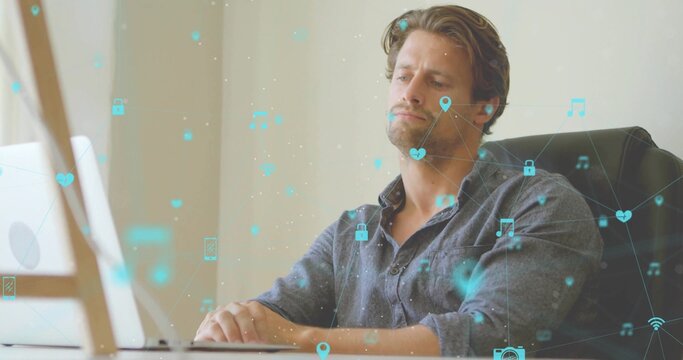 Leaning back man wearing denim shirt, working on white laptop at minimal desk with floating icons