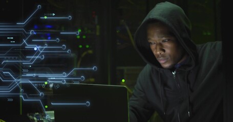 Operating laptop, adult male hacking data beside blinking server racks in data center, copy space