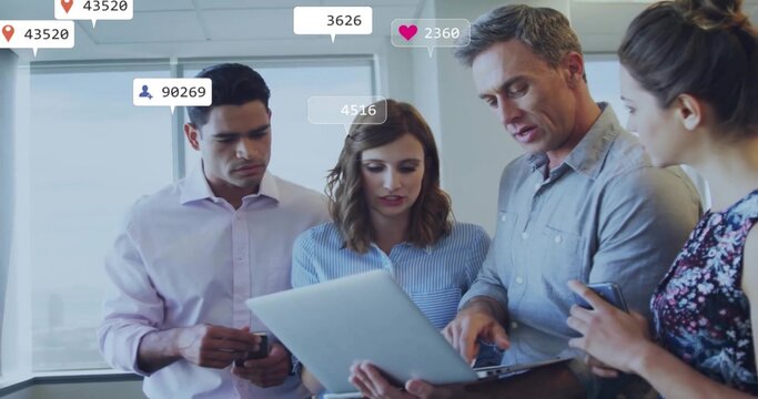 Collaborating professionals working around laptop in office with smartphones and engagement numbers