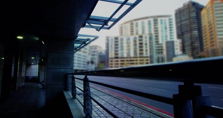 Spanning metal guardrail and glass canopy over urban walkway, highlighting red bus-lane marking
