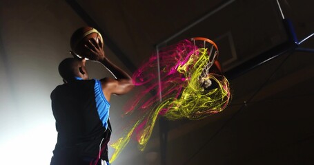 Jumping player wearing athletic jersey gripping ball preparing dunk at gym hoop, with neon trails