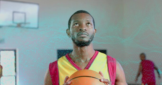 Standing basketball player wearing red jersey holding basketball, gazing toward hoop on gym court - Powered by Adobe