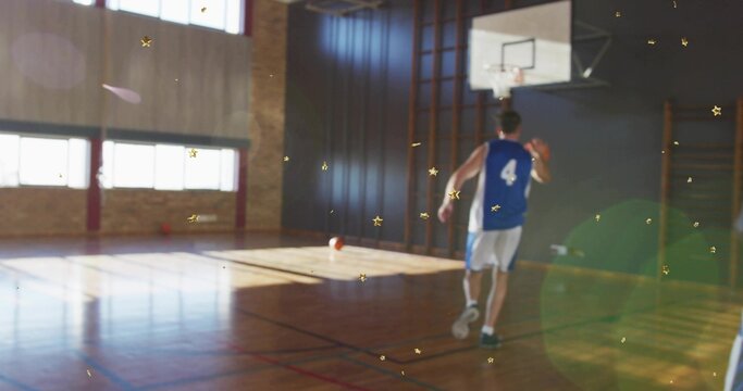 Fototapeta Player in blue-jersey 4 carrying basketball across gym court under sunlit windows, hoop