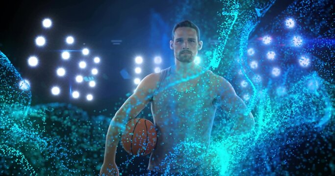 Standing male athlete holding basketball under floodlights midcourt, with turquoise digital streams - Powered by Adobe
