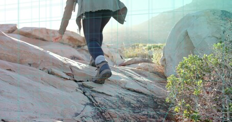 Climbing mid adult hiker ascending weathered rock in desert canyon, with backpack and hiking boots