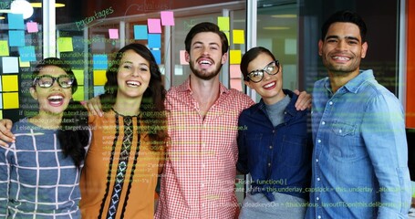 Standing colleagues celebrating in tech office with glass wall showing sticky notes, code snippets
