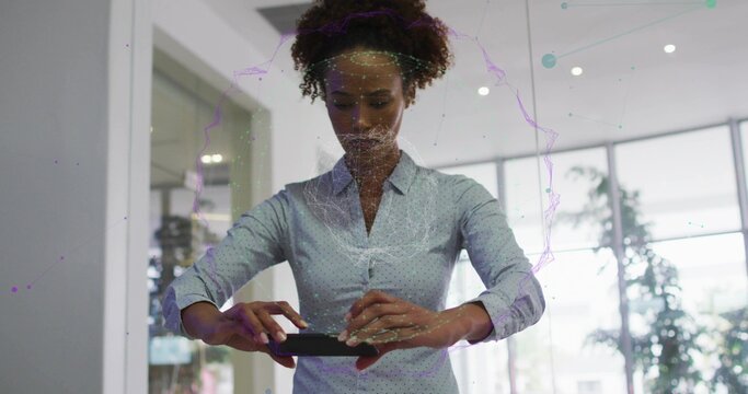 Female professional wearing blue polka dot shirt examining mesh orb, holding smartphone in office