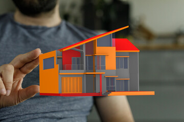 A man holds a colorful architectural model of a house, a concept for new home, house plan, architecture and construction. Housing market and mor © vegefox.com