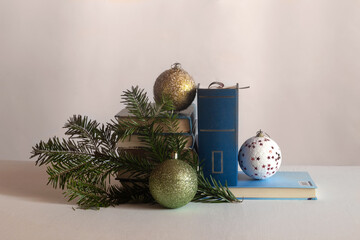 On the table are books, a Christmas tree branch and balls. Horizontal shot.