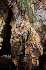 Vadu Crisului Cave in Bihor, Romania, features impressive limestone formations. Stalactites hang from the ceiling, while stalagmites rise from the floor, some meeting to form columns