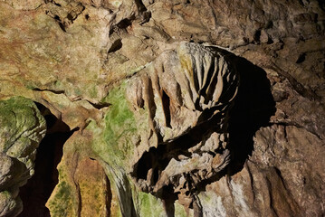 Vadu Crisului Cave in Bihor, Romania, features impressive limestone formations. Stalactites hang from the ceiling, while stalagmites rise from the floor, some meeting to form columns