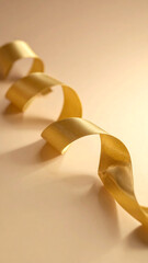 Luxurious golden ribbon elegantly curled on a soft pastel background. A perfect minimalistic holiday scene symbolizing warmth and celebration