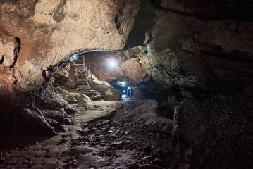 Vadu Crisului Cave in Bihor, Romania, features impressive limestone formations. Stalactites hang from the ceiling, while stalagmites rise from the floor, some meeting to form columns