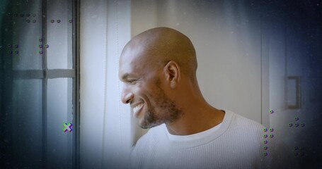 Mid adult man turning head smiling by window while tech glitch graphics appearing reflecting memory - Powered by Adobe