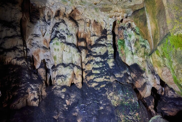 Vadu Crisului Cave in Bihor, Romania, features impressive limestone formations. Stalactites hang from the ceiling, while stalagmites rise from the floor, some meeting to form columns