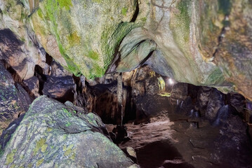 Vadu Crisului Cave in Bihor, Romania, features impressive limestone formations. Stalactites hang from the ceiling, while stalagmites rise from the floor, some meeting to form columns