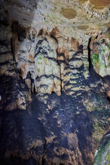 Vadu Crisului Cave in Bihor, Romania, features impressive limestone formations. Stalactites hang from the ceiling, while stalagmites rise from the floor, some meeting to form columns