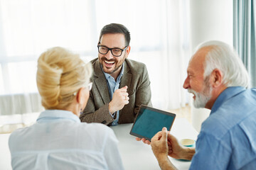 Senior couple having a meeting with an agent, businessman, salesperson or doctor in his office