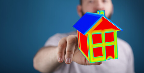 A person holds a thermal image of a house, representing concepts of energy efficiency, housing and property ownership. The image uses a temperat