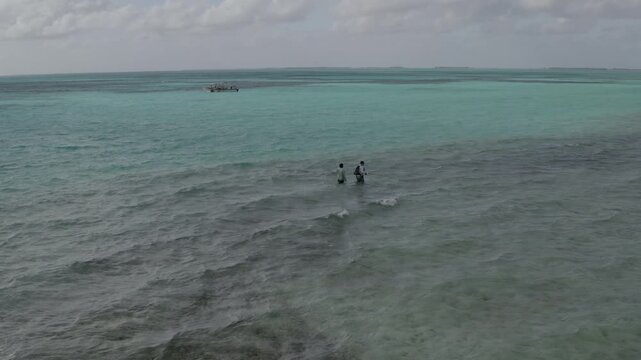 Stunning 4K aerial footage of two fly fishermen wading across the shallow turquoise flats of Kiritimati (Christmas Island), Kiribati. Crystal-clear water, expansive coral flats, and the remote tropica