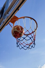 Basketball making a score with blue sky background