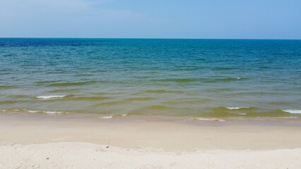 A serene coastal scene with the ocean stretching to the horizon under a clear sky. A sandy beach in the foreground invites relaxation and tranquility.