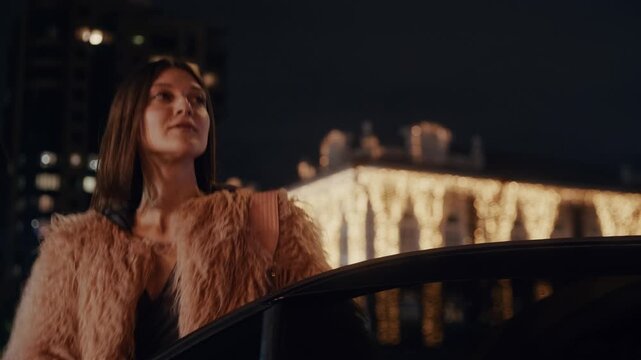 A young, beautiful woman arrives at her destination in a yellow taxi and steps out onto the city street, surrounded by the glow of lights and the buzz of nightlife.