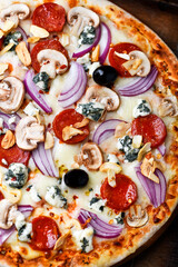 Obraz premium Pizza with chorizo ​​sausage, mozzarella cheese, and black olives. Rustic wooden background. Soft focus. 