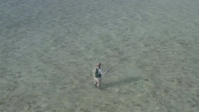 Stunning 4K aerial footage of two fly fishermen wading across the shallow turquoise flats of Kiritimati (Christmas Island), Kiribati. Crystal-clear water, expansive coral flats, and the remote tropica