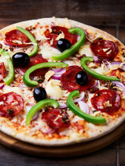 Pizza with salami, mozzarella cheese and jalapeno pepper. Wooden background. Soft focus.	