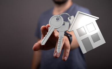 Man holding keys with a house charm, representing new home ownership and real estate purchase....