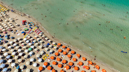 Aerial view of many umbrellas and beach resorts on a dreamlike landscape. The sandy coast with turquoise and crystal clear sea is located in San Vito Lo Capo, in the province of Trapani, Sicily, Italy