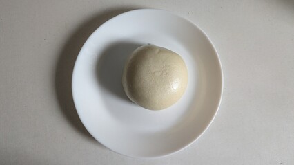 Traditional Chinese Steamed Mantou Bun. Soft traditional Chinese mantou bun steamed and served on a white plate, highlighting its fluffy texture and classic appearance.