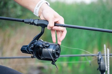 Man holding fishing rod with reel outdoors. Close up of a mans hand holding a fishing rod
