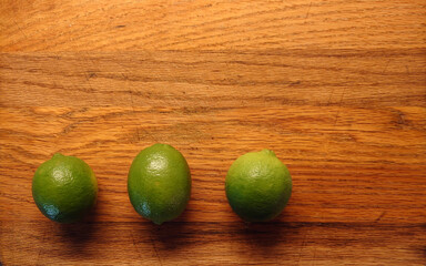 three persian limes on a wooden cutting board