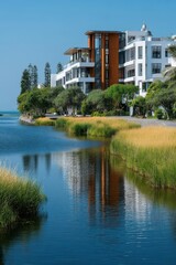 Fototapeta premium Modern waterfront building surrounded by greenery and calm blue waters
