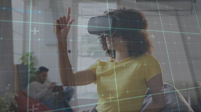 Woman wearing VR headset raising right finger and dragging virtual grid during technology demo