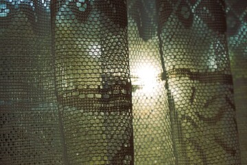 Alte transparente Gardine vor Fenster und Himmel mit weißem Sonnenlicht bei Sonnenuntergang am Abend im Sommer