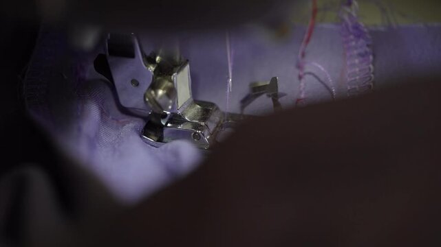 Sewing a smooth hem on a purple fabric with a sewing machine in a well-lit workspace