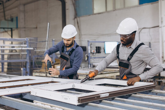 Factory workers assembling pvc windows and doors in production line - Powered by Adobe
