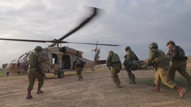 Cinematic slow motion ground view of a military helicopter with blur faces special forces soldiers showing teamwork during a medical evacuation operation at sunset