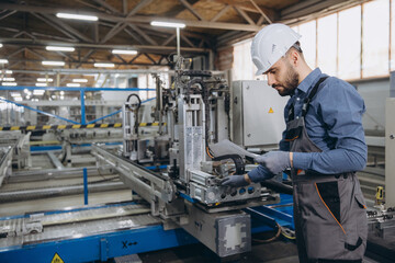 Factory worker operating machinery for aluminum and pvc windows and doors production