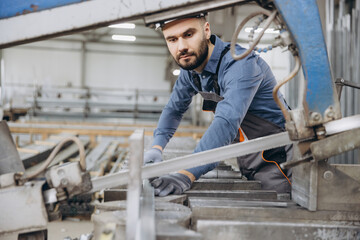 Factory worker cutting aluminum profiles for pvc windows and doors production