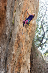 A woman climbs a rock, a strong girl trains strength and endurance, extreme sport, rock climbing on natural terrain, a rock climber climbs.