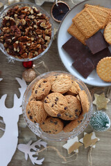 Various Christmas decorations, cookies, chocolate and nuts on wooden background. Flat lay.