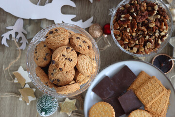 Various Christmas decorations, cookies, chocolate and nuts on wooden background. Flat lay.